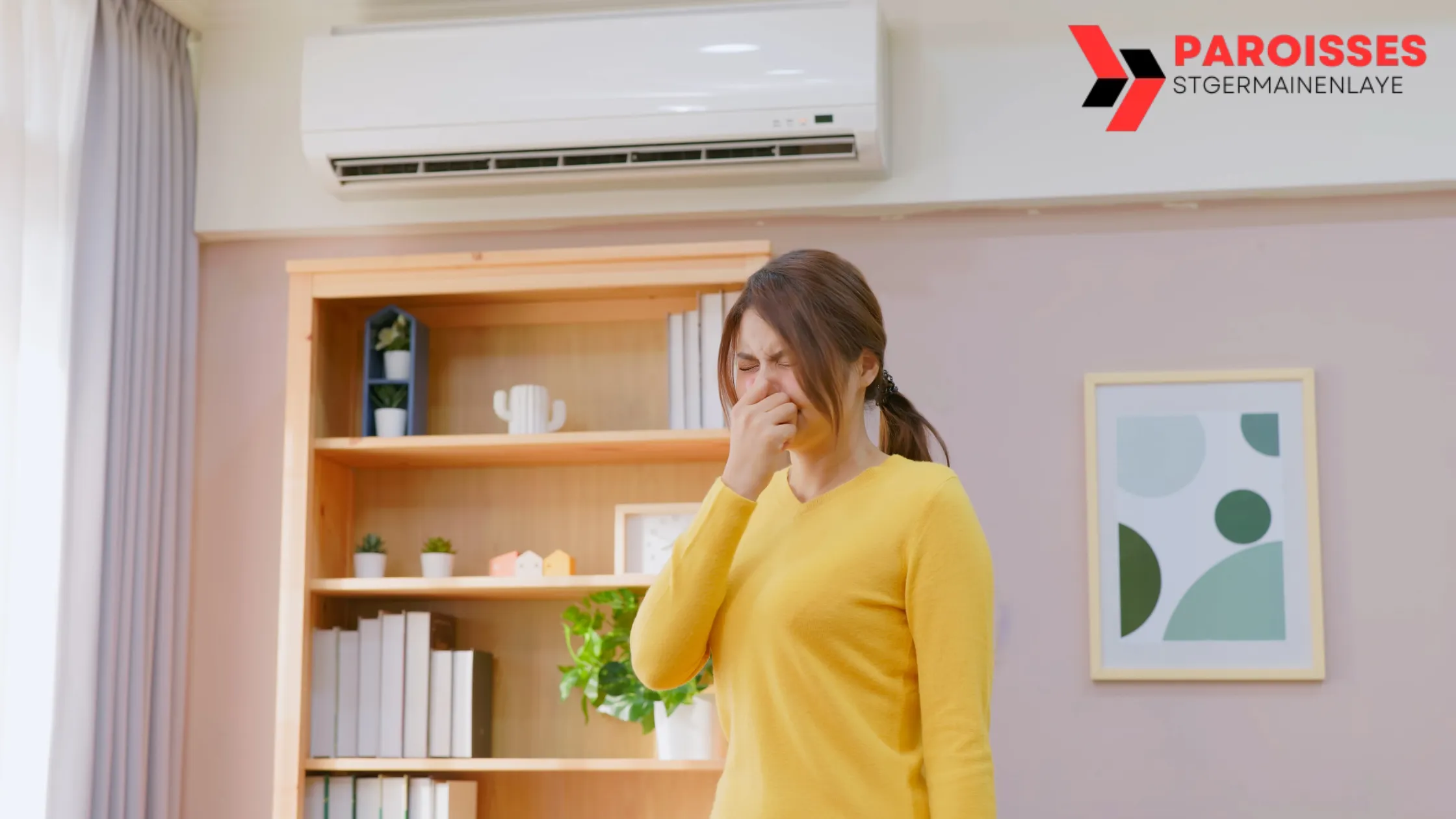 A woman stands in front of an air conditioner, sneezing while holding her nose, suggesting illness. Focus keyword: "Can AC Cold Make You Sick?"