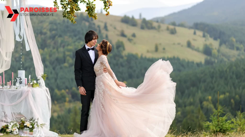 "Can You Get Invited to a Wedding?" A bride in a flowing lace gown embraces the groom against a picturesque mountain backdrop, with an elegant, softly decorated outdoor setting, capturing a magical moment of love.